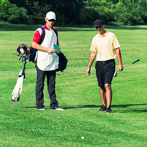 高尔夫球手和球童在高尔夫球场上球躺图片