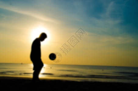 人在沙滩上踢足球的剪影模糊风格图片