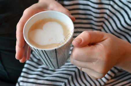 年轻女人的手握着一个杯子咖啡图片