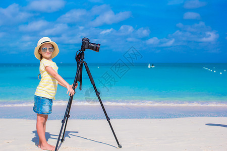 在热带沙滩打电话拍照的小可爱女孩照片图片