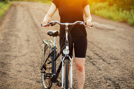 自行车的细节骑自行车的女人在日出或日落时在的灯光下骑自行车年轻的女孩和他的自行车在阳光明媚的日子里骑自行车的女人运动健康的图片