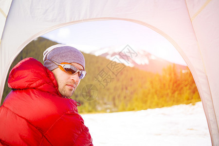 一位登山者坐在帐篷里的肖像背景是山脉图片