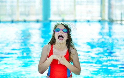 小女孩摆姿势戴着游泳眼镜在游泳池里图片