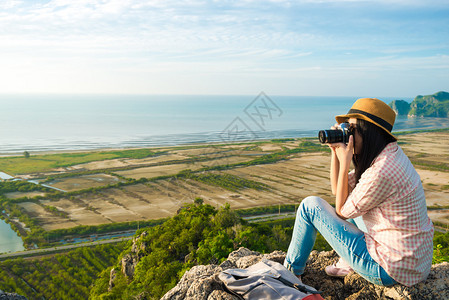 坐在山顶的亚洲时髦女孩拿着相机坐图片