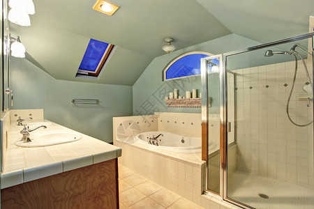 带拱形天花板和天窗的旧象牙浴室玻璃淋浴间的视图与瓷砖墙装饰和白色浴缸上面的架子上装饰着蜡烛图片