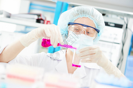 药学和化学主题女医学科研人员或药房医生拿着装有粉红色液体溶液的烧瓶图片