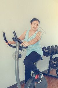 亚洲胖女人在健身房训练自行车图片