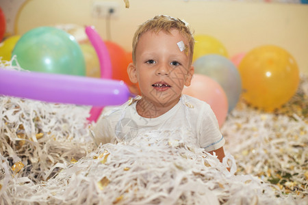 小男孩跳跃和开心庆祝生日一个孩子的肖像抛出了多色金属丝和纸屑儿童派对在闪发光的五彩纸屑淋浴下快乐图片