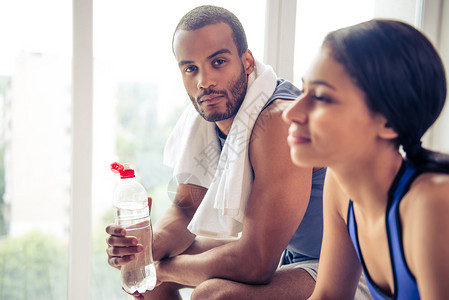健身后休息的运动服装中美黑人夫妇的侧面景象Guy拿着一瓶图片