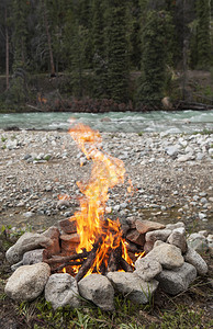 夏季加拿大育空地区惠顿河边的岩石环上燃烧营火图片