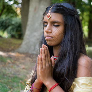 美丽的印度年轻女在公园祈祷印度教宗教精图片