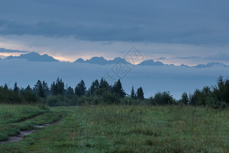 山中日出时穿过草地的道路背景图片