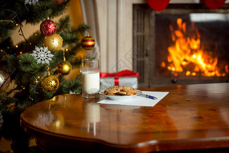 在燃烧的壁炉和圣诞树旁的桌子上图片