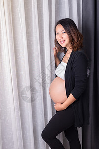 孕妇站在房间窗户背景图片