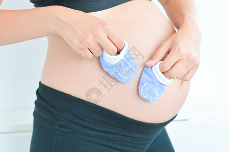 孕妇把蓝色小袜子放在肚子上图片