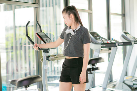 漂亮的亚洲女子在健身房运动在自行车健身图片