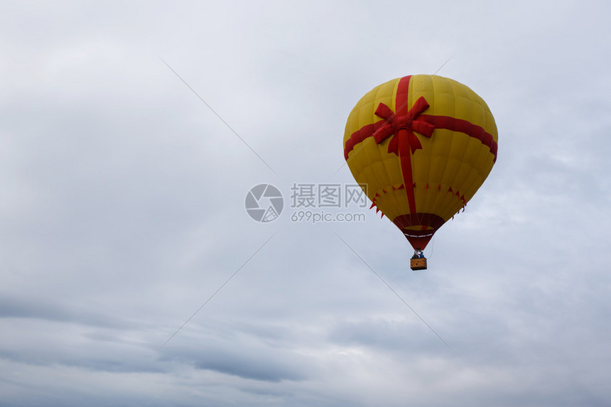 带红丝带的黄色热气球升起图片