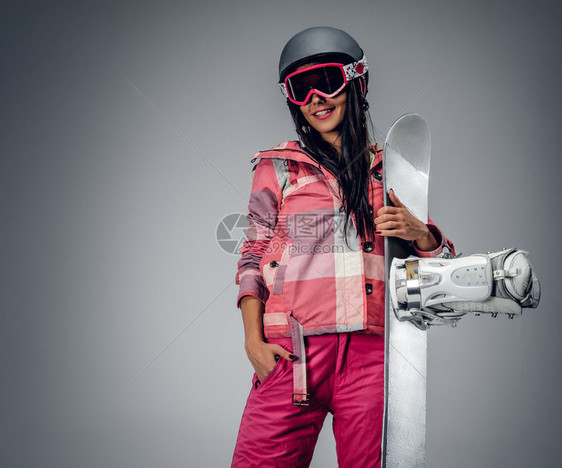 穿着粉红色滑雪服的活跃女肖像在灰色背图片