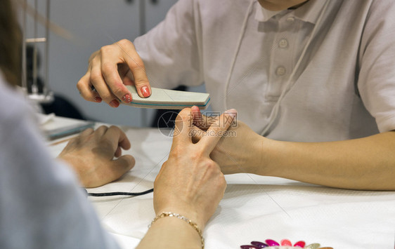 修甲师主使指甲在女手掌上贴钉有图片