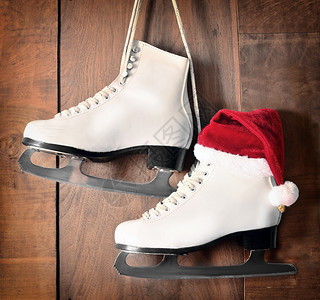 用于花样滑冰的白色溜冰鞋挂在木制背景上图片