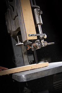一个工匠用带锯切割一块木板图片