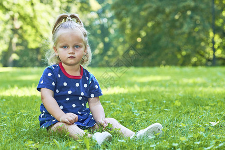 小女孩坐在公园的草地上图片