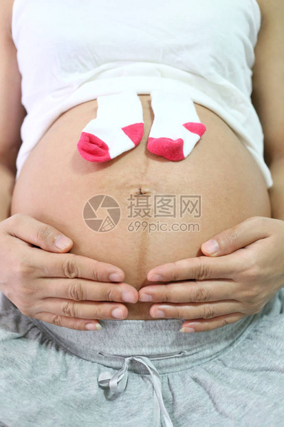 孕妇把袜子放在肚子里的爱这个婴儿的概念上图片