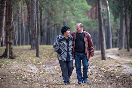 走在森林里的老夫妇一起度过美好的时光在秋天或春天的森林里一图片