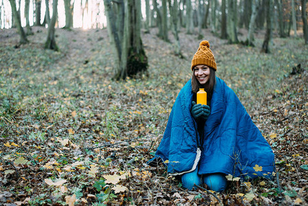 秋天森林里拿着热水瓶的年轻女人图片