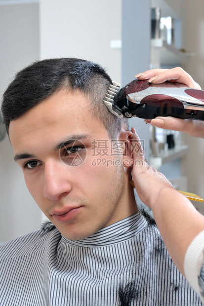 用电动推剪给小男孩理发的理发店图片