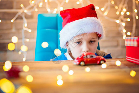孩子在家里玩圣诞老人的玩具快乐有趣的孩子男孩玩礼物背景上的灯光散景图片