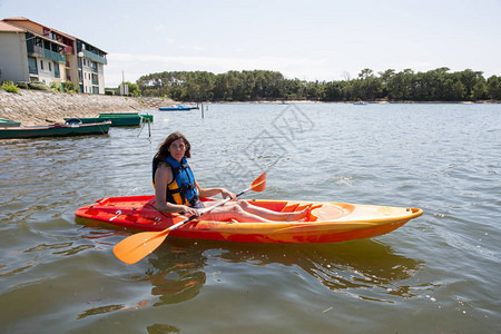 穿红色黄色皮艇的漂亮运动女运动员在海中或海滩河附图片