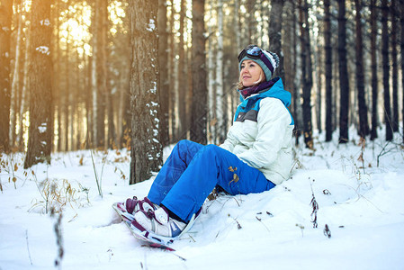 带滑雪板的女子滑雪板坐在雪地上图片