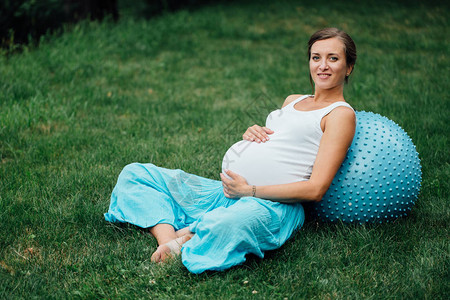 怀孕瑜伽产前妇用fitball做不同的锻炼在公园的草地上图片