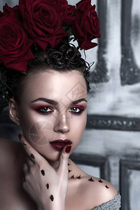 美容时装模特女人的脸与红玫瑰花朵的肖像红唇和指甲美丽的黑发女人图片