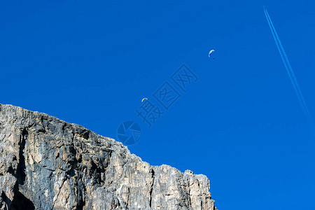 悬挂式滑翔机滑翔伞在天空白云岩山脉背景图片
