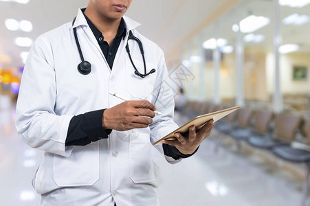 医生手持平板电脑与听诊器设备抽象照片模糊的医院背景图片