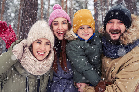 冬天站在白雪皑的森林里的幸福四口之家的低视角紧身骑士家庭在户外共度时图片