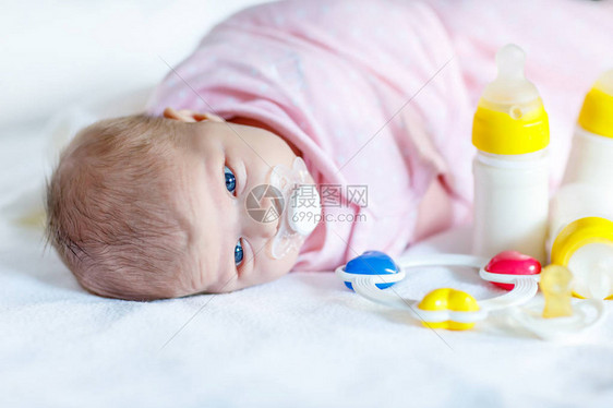 可爱的新生女婴与奶瓶拨浪鼓和奶嘴婴儿配方奶粉新出生的孩子图片