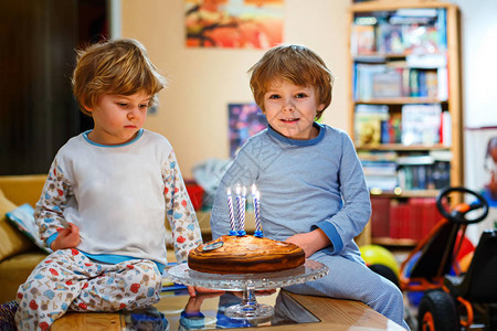 在室内的自制烤蛋糕上吹蜡烛兄弟姐妹孩子的生日派对关于礼物图片