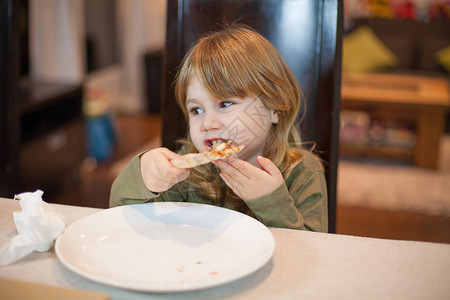 三岁金发饥饿的孩子用手吃披萨图片