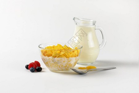 满碗玉米片和一壶牛奶在非白色背背景图片