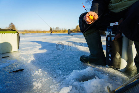 冬季钓鱼冰钓冰上渔夫从井里钓鱼图片