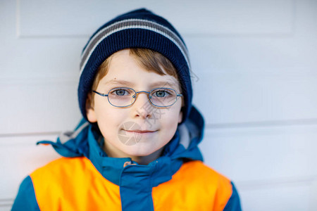 可爱的小学生男孩戴着眼镜和五颜六色的冬季时尚衣服的画像孩子微笑着玩相机冬季春季或秋季时尚门图片