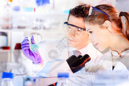 生命科学研究人员在实验室观察溶液化学实验室有吸引力的年轻博士生和她的博士后导师科学家在烧瓶中观察蓝色指图片