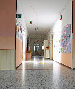 在幼儿园的长走廊内墙上挂着儿童画图背景图片
