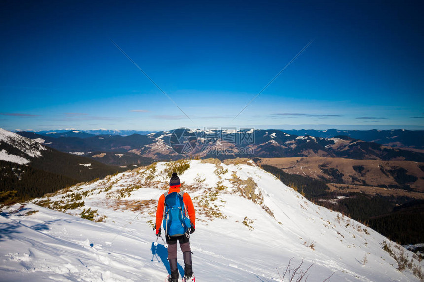 穿着雪鞋和登山杖的人在山上爬山图片