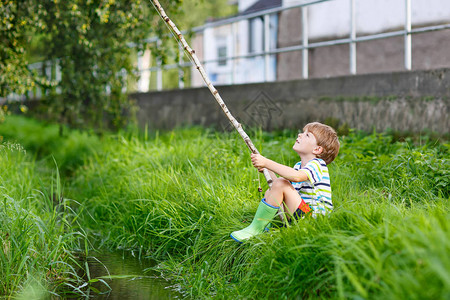活跃的学龄前儿童男孩在阳光明媚的夏日用自制的鱼竿在河上钓鱼快乐的孩子玩得开心户外儿图片
