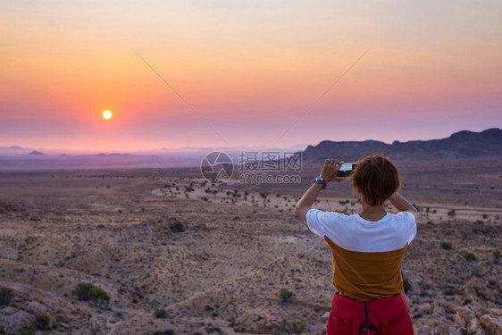 游客用智能手机拍摄纳米布沙漠贫瘠山谷的壮丽景色图片