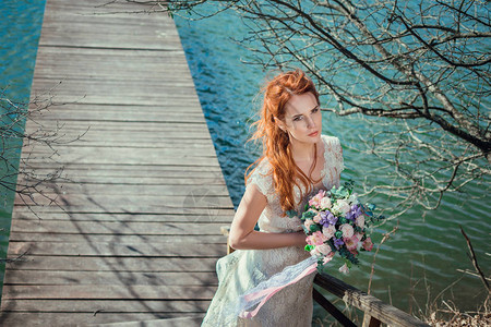 穿着婚纱的漂亮年轻女孩在水边码头上图片